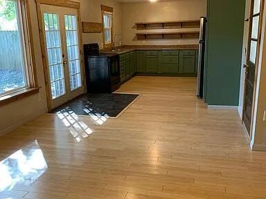 kitchen with stove, french doors, green cabinets, and a healthy amount of sunlight