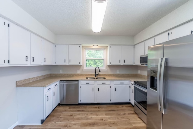 kitchen featuring white cabinets, sink, appliances with stainless steel finishes, and a textured ceiling