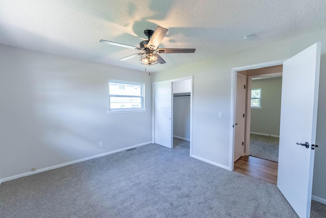 unfurnished bedroom featuring carpet flooring, ceiling fan, a textured ceiling, and multiple windows