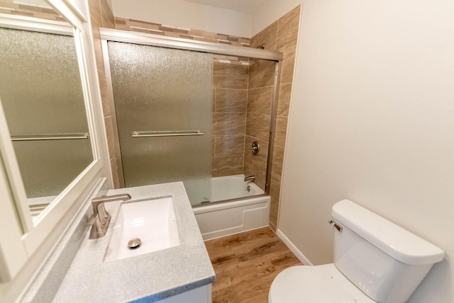 full bathroom with toilet, vanity, wood-type flooring, and combined bath / shower with glass door