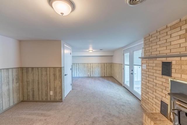 spare room featuring light carpet, wooden walls, and french doors