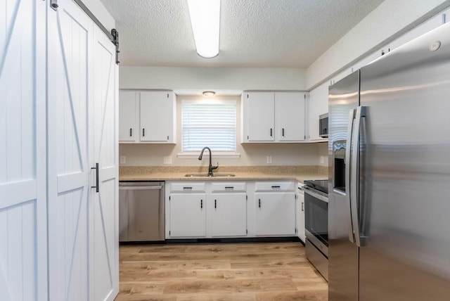1610 Good Hard Dr, West Plains, MO 65775 - kitchen with appliances with stainless steel finishes, light countertops, white cabinetry, light wood-style flooring, and a textured ceiling