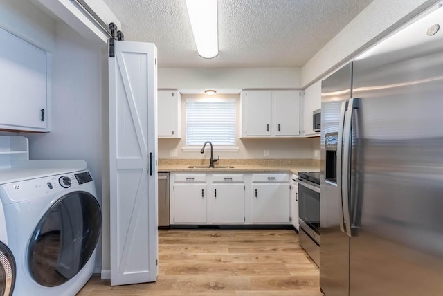 1610 Good Hard Dr, West Plains, MO 65775 - kitchen featuring appliances with stainless steel finishes, light countertops, white cabinetry, washer and dryer, and a textured ceiling
