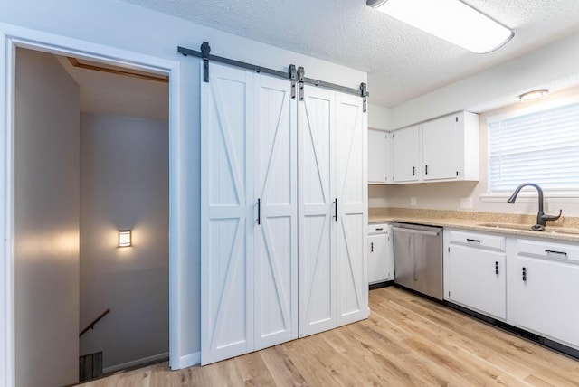 1610 Good Hard Dr, West Plains, MO 65775 - kitchen with dishwasher, light wood-style flooring, a textured ceiling, white cabinetry, and a barn door