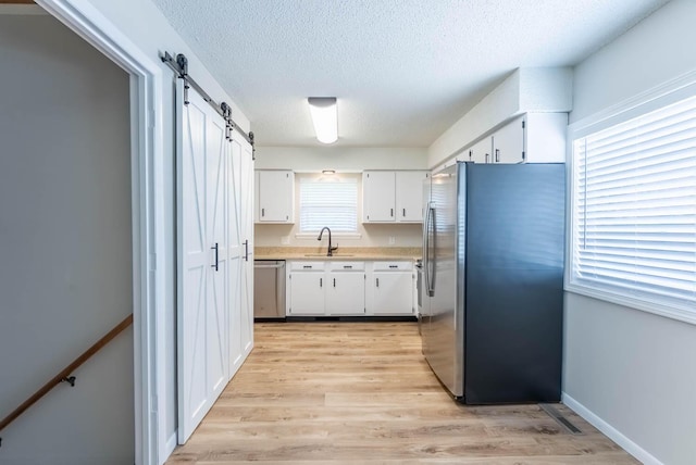 1610 Good Hard Dr, West Plains, MO 65775 - kitchen with stainless steel appliances, a textured ceiling, a barn door, light countertops, and white cabinets