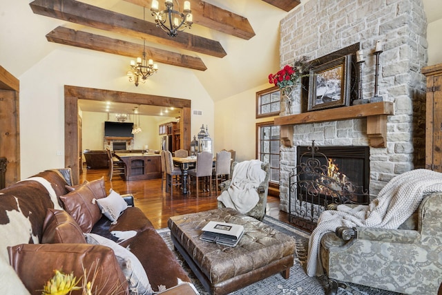 living room with hardwood / wood-style floors, vaulted ceiling with beams, an inviting chandelier, and a stone fireplace