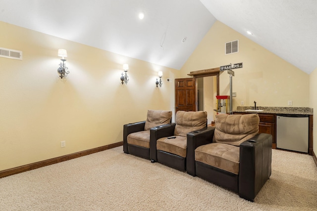 cinema room featuring light carpet, lofted ceiling, and indoor wet bar