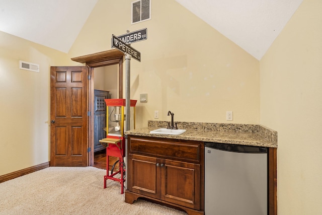 bar featuring light carpet, light stone counters, sink, fridge, and lofted ceiling