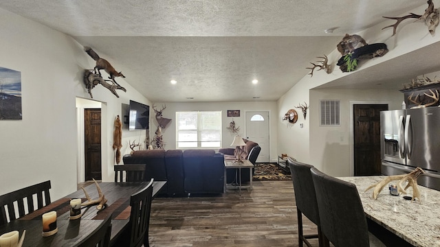 dining area with dark hardwood / wood-style flooring, a textured ceiling, and vaulted ceiling