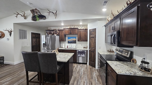 kitchen featuring hardwood / wood-style floors, sink, vaulted ceiling, appliances with stainless steel finishes, and dark brown cabinetry