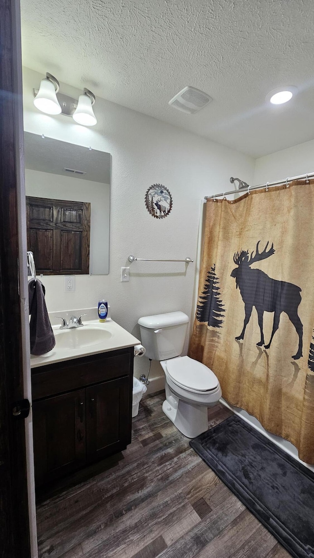 bathroom with vanity, a shower with curtain, toilet, a textured ceiling, and wood-type flooring