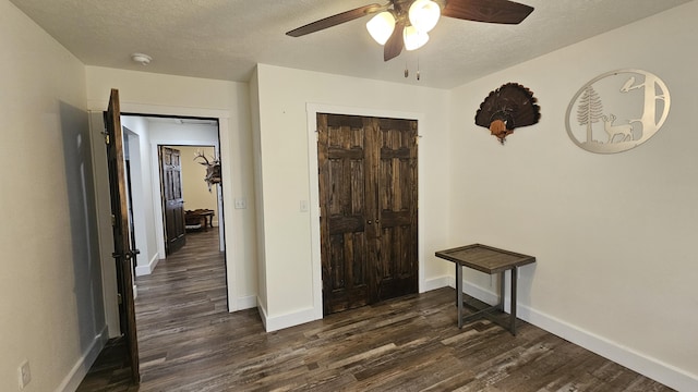 bedroom featuring baseboards, a textured ceiling, dark wood finished floors, and a ceiling fan