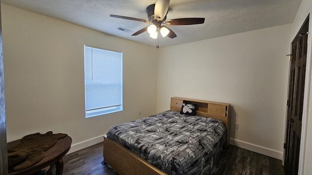 bedroom featuring a ceiling fan, baseboards, visible vents, dark wood-type flooring, and a textured ceiling