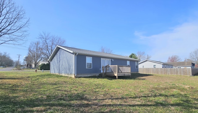 rear view of house with a deck, a yard, and fence