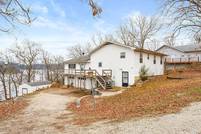 rear view of property featuring driveway, a deck, and stairs