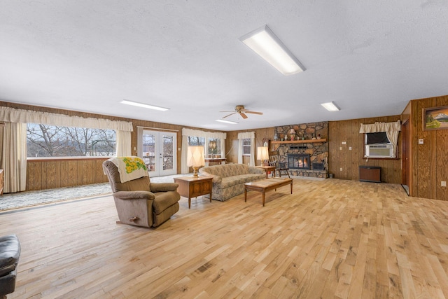 living area featuring french doors, a fireplace, wood finished floors, and wooden walls