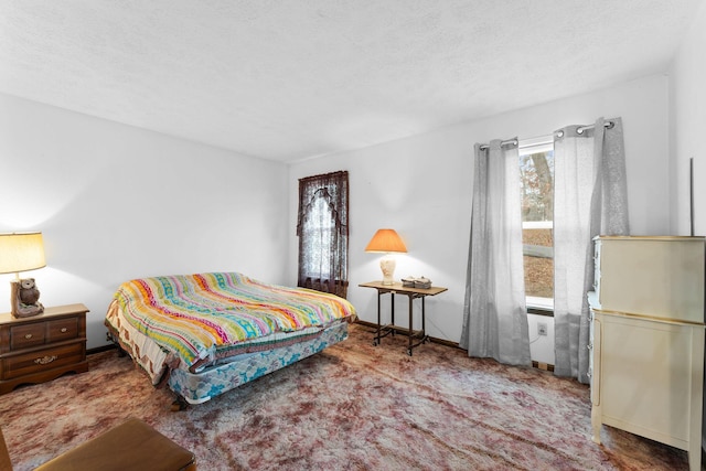 bedroom featuring multiple windows, a textured ceiling, and carpet flooring