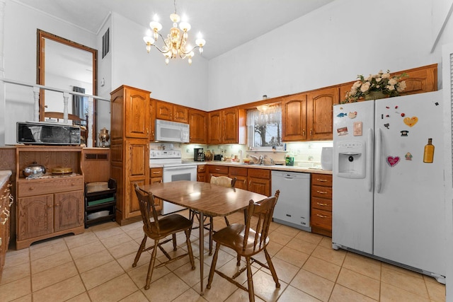 kitchen with light tile patterned floors, white appliances, backsplash, and brown cabinets