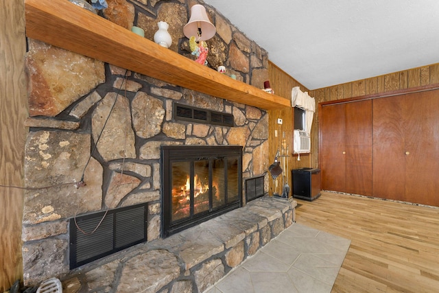 details with a stone fireplace, wood finished floors, and visible vents