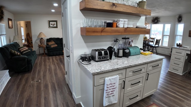 kitchen featuring white cabinets, light stone counters, and dark wood-type flooring