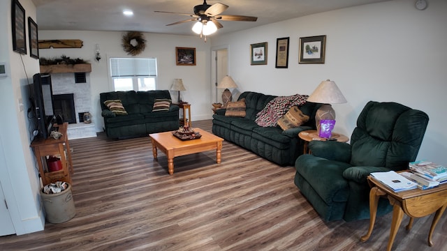 living room with hardwood / wood-style flooring, ceiling fan, and a brick fireplace