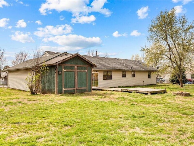 back of house featuring an outbuilding, a wooden deck, and a lawn