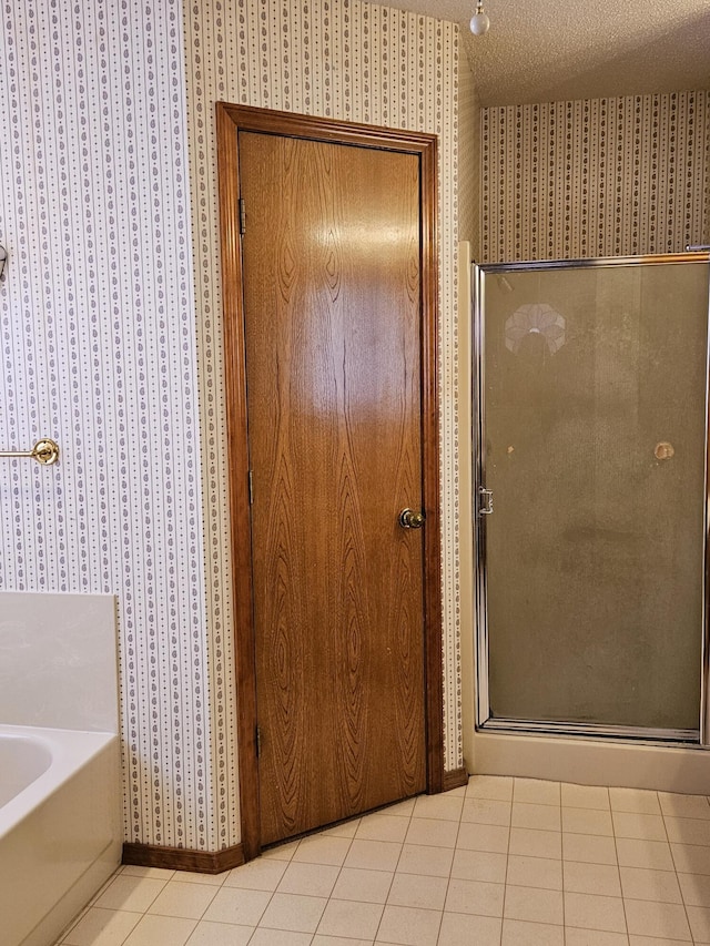 bathroom with tile patterned floors, independent shower and bath, and a textured ceiling