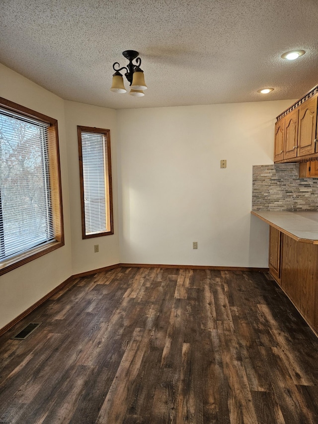 unfurnished dining area featuring dark hardwood / wood-style flooring and a textured ceiling