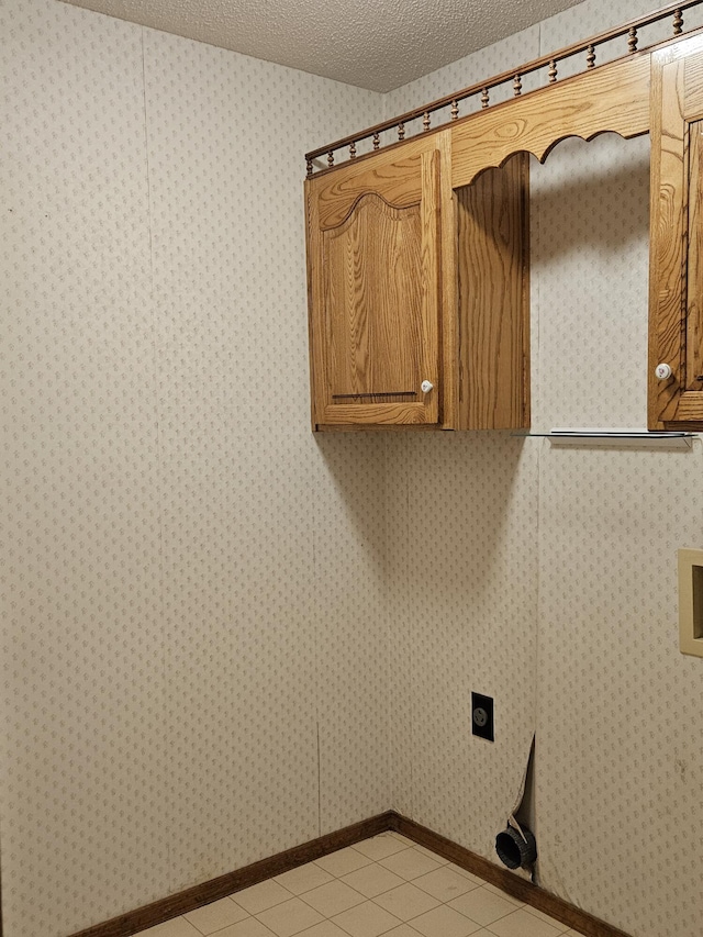 washroom with cabinets, light tile patterned floors, a textured ceiling, and electric dryer hookup