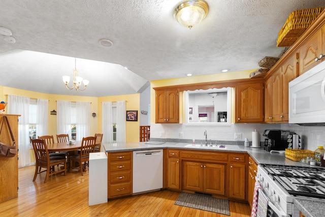 kitchen featuring decorative backsplash, white appliances, sink, light hardwood / wood-style flooring, and a notable chandelier