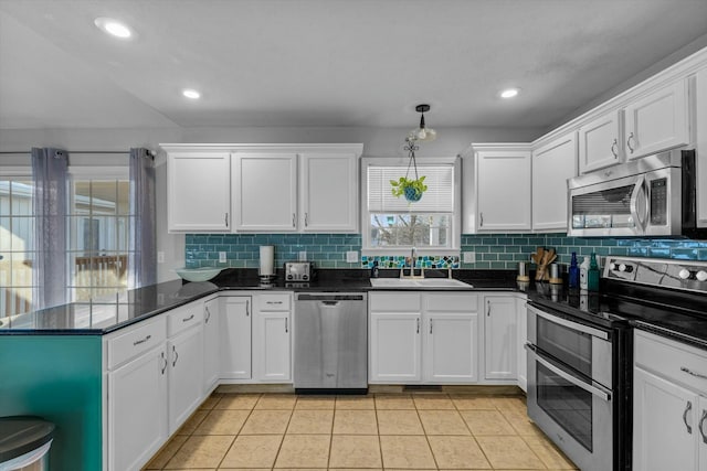 kitchen with white cabinets, stainless steel appliances, sink, kitchen peninsula, and light tile patterned floors