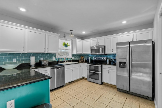 kitchen featuring white cabinetry, appliances with stainless steel finishes, tasteful backsplash, light tile patterned flooring, and sink