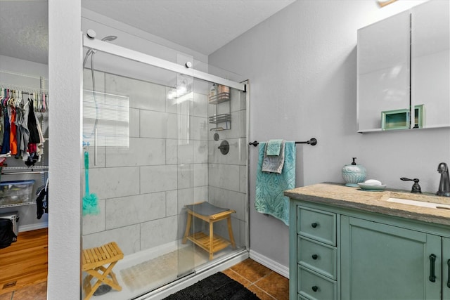 bathroom featuring vanity, tile patterned flooring, a textured ceiling, and a shower with door