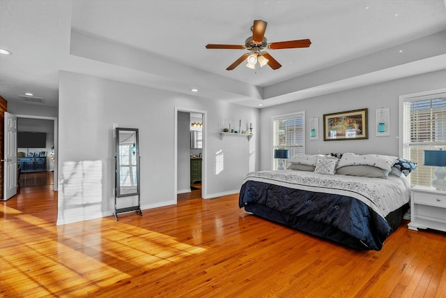 bedroom featuring light wood-type flooring, ceiling fan, and a raised ceiling