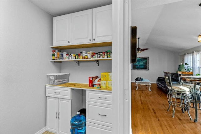 kitchen with ceiling fan, white cabinets, vaulted ceiling, and light hardwood / wood-style flooring