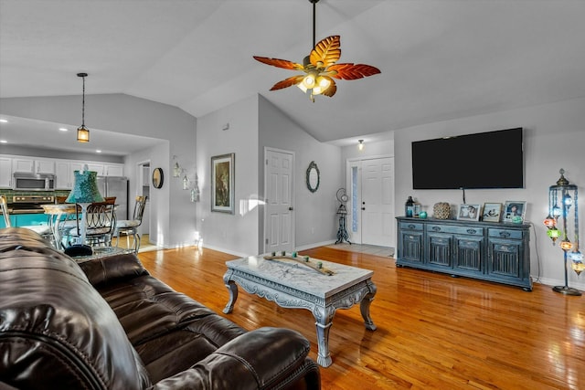 living room with ceiling fan, light wood-type flooring, and vaulted ceiling