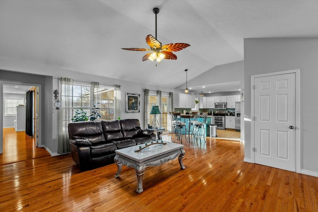 living room featuring ceiling fan, a wealth of natural light, vaulted ceiling, and light wood-type flooring