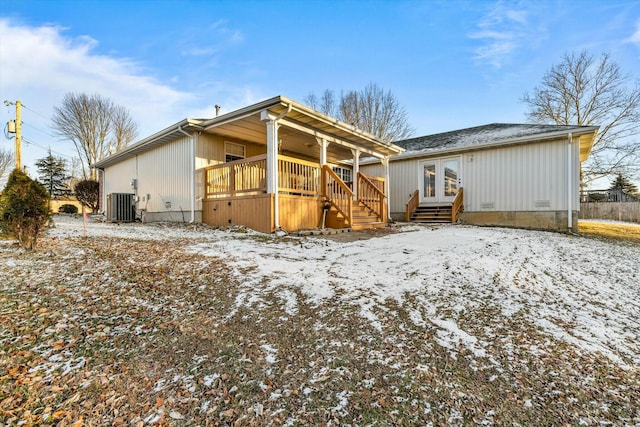 snow covered property featuring central air condition unit and french doors