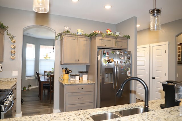 kitchen with light stone counters, sink, decorative light fixtures, and appliances with stainless steel finishes