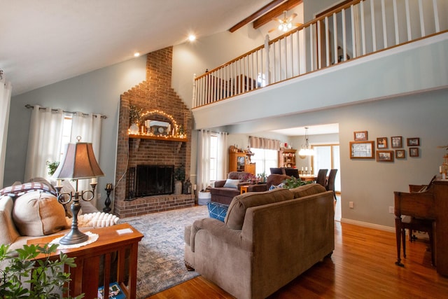 living room with wood-type flooring, high vaulted ceiling, and a brick fireplace