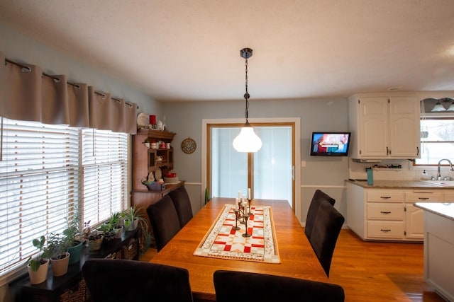 dining area featuring a healthy amount of sunlight, sink, and light hardwood / wood-style floors