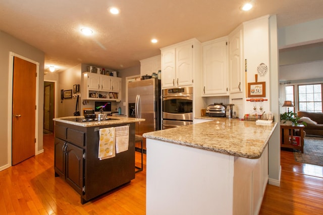 kitchen featuring white cabinetry, stainless steel refrigerator with ice dispenser, light hardwood / wood-style floors, kitchen peninsula, and cooktop