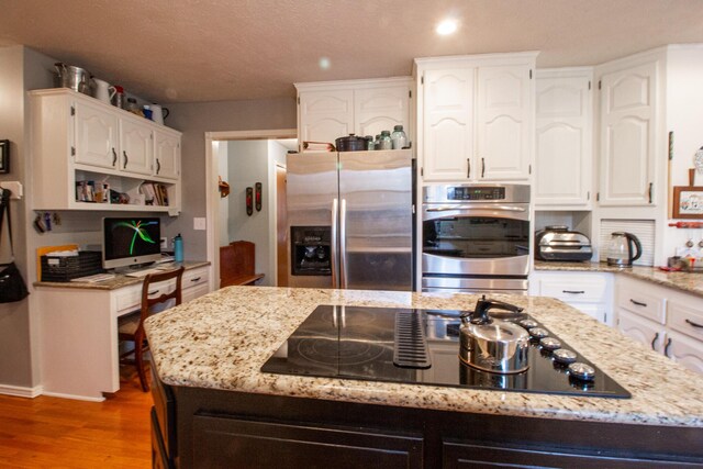 kitchen featuring light stone counters, appliances with stainless steel finishes, hardwood / wood-style floors, and white cabinets