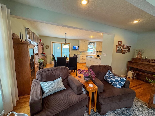 living room featuring sink, a textured ceiling, and light wood-type flooring