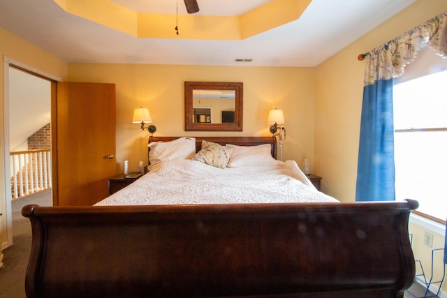 bedroom with ceiling fan and a raised ceiling