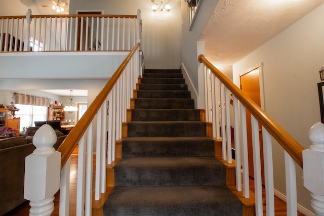 stairway featuring hardwood / wood-style floors, a textured ceiling, and a chandelier