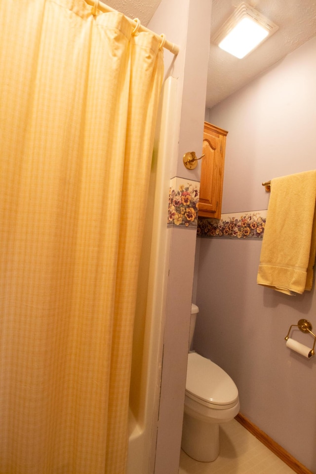 bathroom featuring shower / bath combination with curtain, toilet, and a textured ceiling