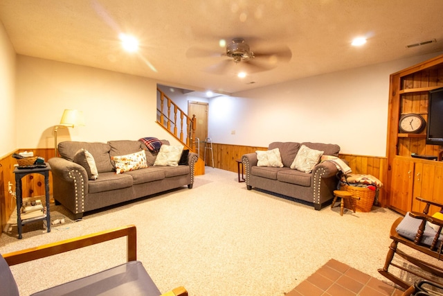 carpeted living room with wooden walls and ceiling fan