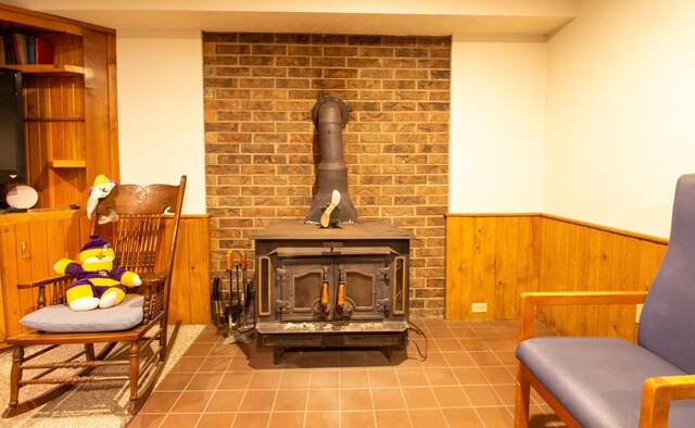 sitting room with a wood stove, tile patterned floors, and wooden walls