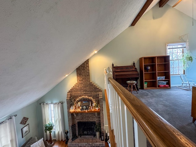 carpeted living room with a fireplace, beam ceiling, high vaulted ceiling, and a textured ceiling